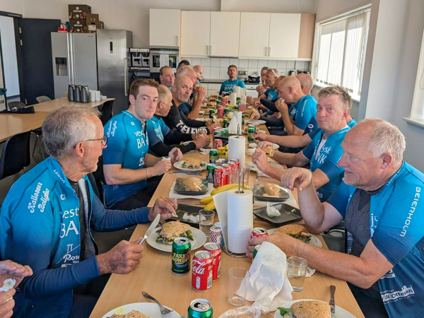 Riders from Lemvig Cycling Club in blue jerseys gathered around a long table in AS SCAN’s canteen, enjoying sandwiches after cycling 155 km.