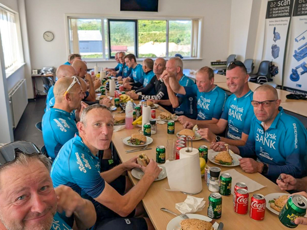 Cyclists from Lemvig Cycling Club sharing lunch in AS SCAN’s canteen with sandwiches, soft drinks and a lively atmosphere.