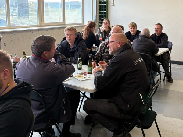 Several employees seated at tables in the workshop, talking together during AS SCAN’s Friday event.